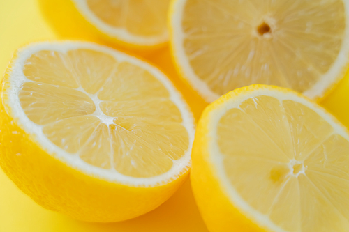 Close up view of fresh cut lemons on yellow surface