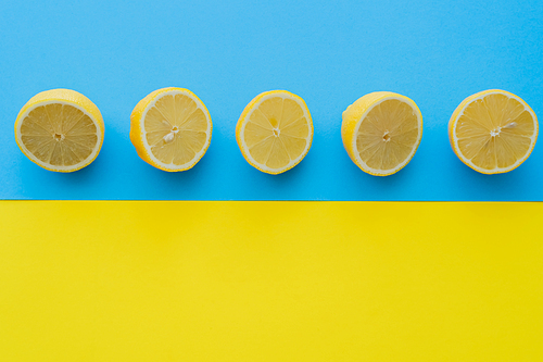 Top view of ripe halves of lemons on blue and yellow background
