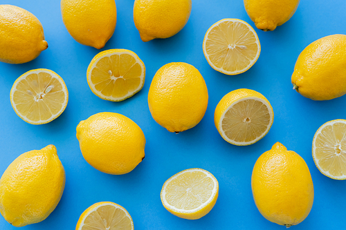 Top view of halves and whole lemons on blue background