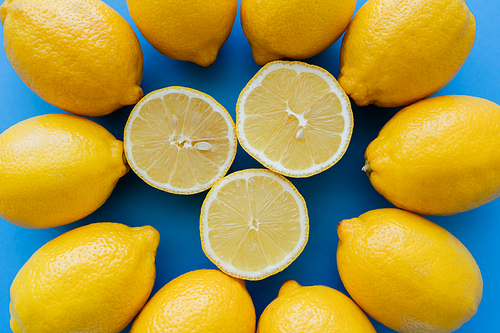 Top view of cut lemons in center of round on blue background