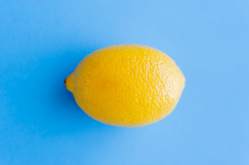 Top view of bright yellow lemon on blue background