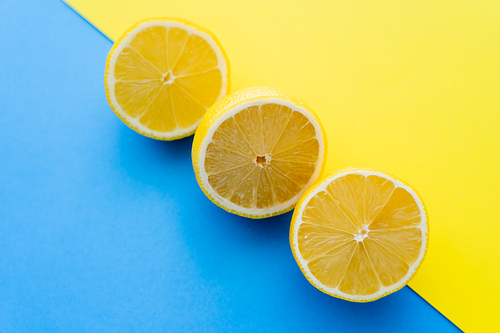 Top view of cut lemons on blue and yellow background