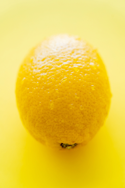 Close up view of wet lemon on yellow background