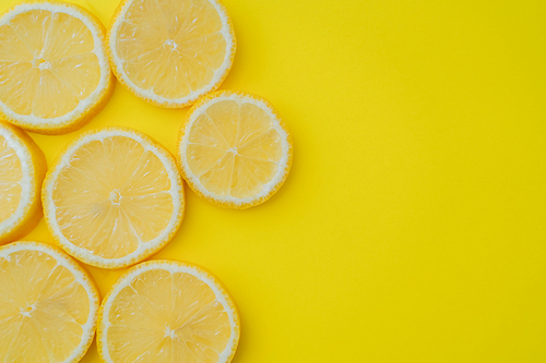 Top view of sliced lemon on yellow background with copy space