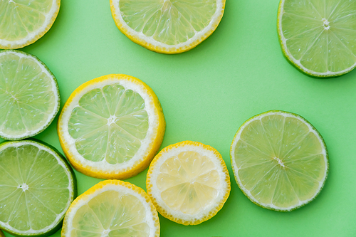 Top view of sliced lemons and limes on green background