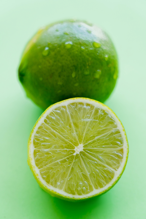 Close up view of juicy cut lime on green background