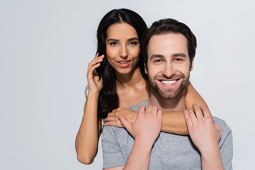 pretty brunette woman  while hugging bearded man in t-shirt  isolated on grey