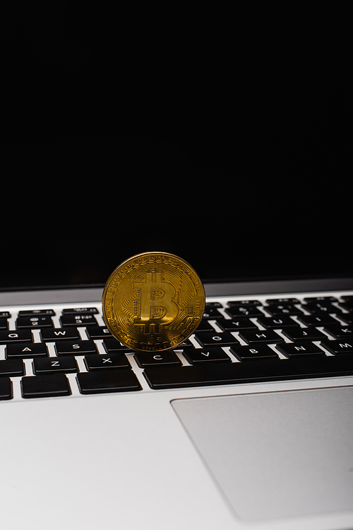 KYIV, UKRAINE - APRIL 26, 2022: Close up view of golden bitcoin on laptop keyboard