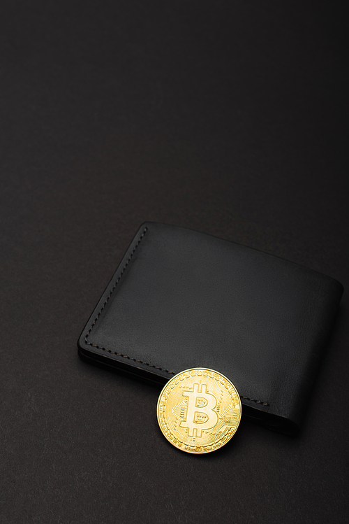 KYIV, UKRAINE - APRIL 26, 2022: High angle view of golden bitcoin on wallet on black background