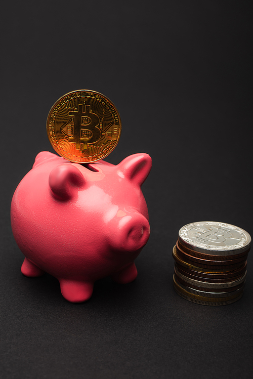 KYIV, UKRAINE - APRIL 26, 2022: Close up view of bitcoin on piggy bank on black background