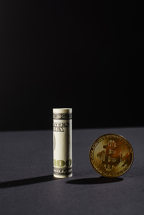 KYIV, UKRAINE - APRIL 26, 2022: Close up view of golden bitcoin and dollar on black background