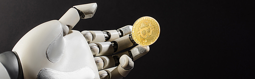 KYIV, UKRAINE - APRIL 26, 2022: Robotic hand and golden crypto coin isolated on black, banner