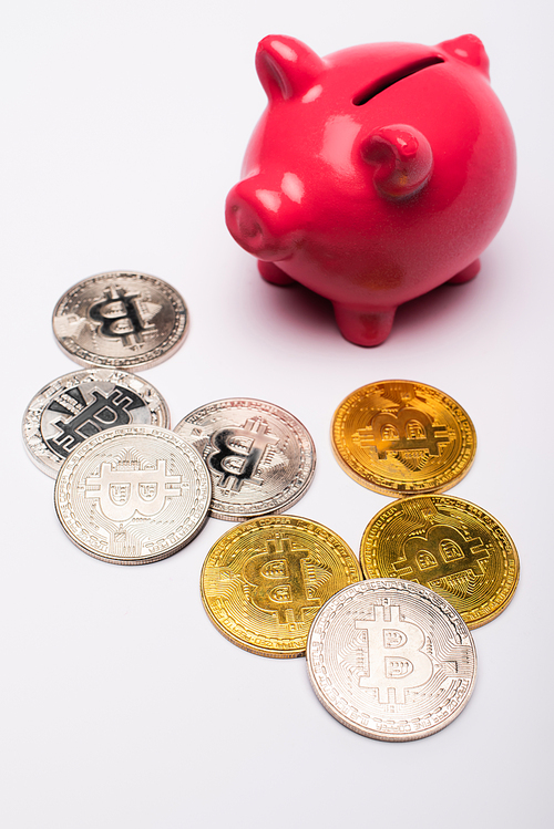KYIV, UKRAINE - APRIL 26, 2022: Close up view of bitcoins and piggy bank on white background