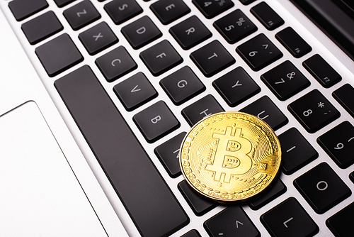 KYIV, UKRAINE - APRIL 26, 2022: Close up view of golden bitcoin on laptop keyboard