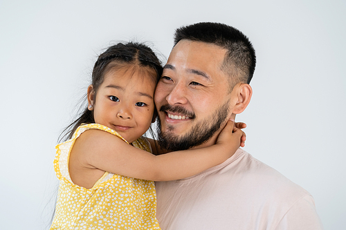 cheerful asian daughter hugging happy father isolated on grey