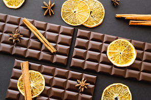 Top view of cinnamon and anise on chocolate bars on black background