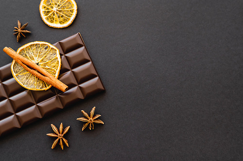 Top view of cinnamon, anise and orange slice on chocolate on black background
