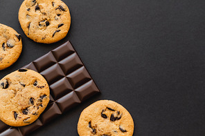 Top view of cookies and chocolate bar on black surface