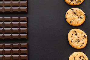 Flat lay with chocolate bars and cookies on black background