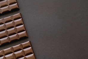 Top view of dark chocolate bars on black surface with copy space
