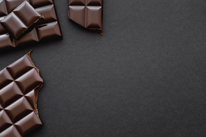 Top view of dark chocolate on black surface with copy space