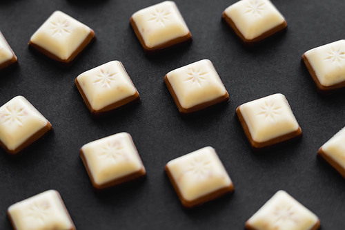 Close up view of white and milk chocolate pieces on black background