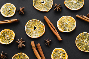 Top view of dry orange slices, cinnamon and anise on black background