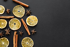 Top view of dry anise, orange slices and cinnamon sticks on black background