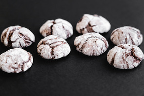 Close up view of biscuits with powdered sugar on black surface