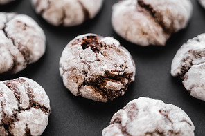 Close up view of baked biscuits with powdered sugar on black surface