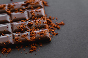 Close up view of cocoa powder on chocolate on black background