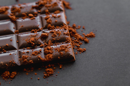 Close up view of cocoa powder on chocolate on black background