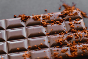 Close up view of dry cocoa powder on natural chocolate on black background