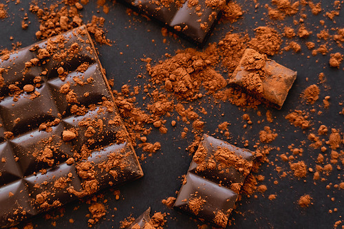 Top view of natural cocoa powder on chocolate on black surface