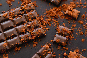 Top view of dark chocolate and coca powder on black background