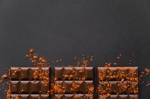 Top view of chocolate bars with dry cocoa powder on black surface