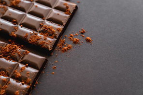 Close up view of natural cocoa on chocolate on black background with copy space