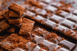 Close up view of dry cocoa powder on chocolate on dark background