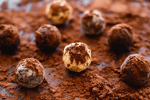 Close up view of tasty candies with cocoa on black background
