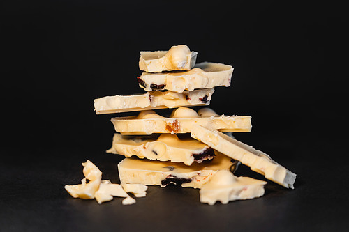Close up view of pieces of white chocolate with nuts on black background
