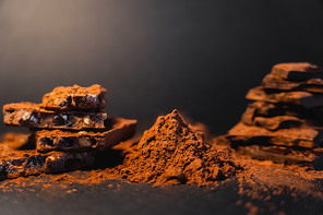 Close up view of dry cocoa and blurred chocolate on black background
