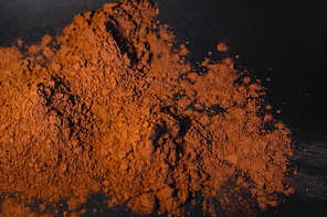Top view of natural brown cocoa powder on black background