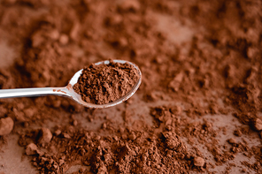 High angle view of cocoa in spoon and on brown background