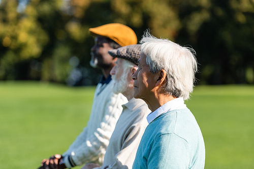 side view of asian senior man near interracial friends