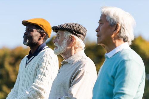 senior man in flat cap near interracial friends