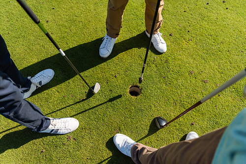 high angle view of senior friends standing with golf clubs on lawn