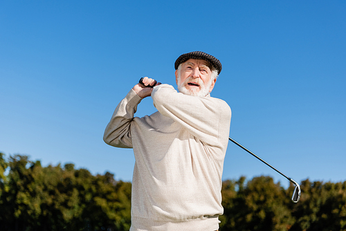 bearded and senior man holding golf club while playing outdoors