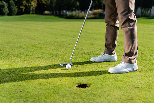 cropped view of man in white sneakers playing golf on lawn