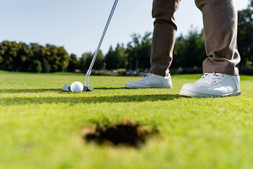 partial view of man in white sneakers playing golf on lawn