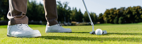 cropped view of man in white sneakers playing golf on lawn, banner